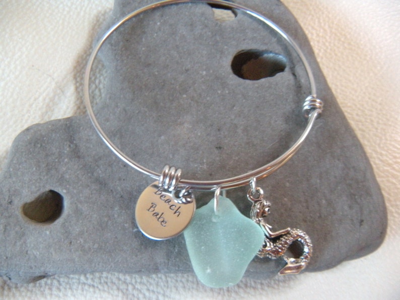 May include: A silver charm bracelet with a sea glass charm, a mermaid charm, and a charm that says "Beach Babe".