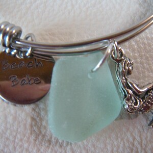 May include: A silver charm bracelet with a sea glass charm, a mermaid charm, and a charm that says "Beach Babe".