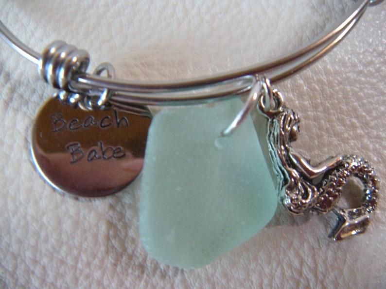 May include: A silver charm bracelet with a sea glass charm, a mermaid charm, and a charm that says "Beach Babe".