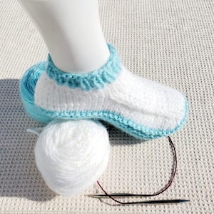 May include: A white and turquoise knitted sock with a white ball of yarn and two knitting needles.