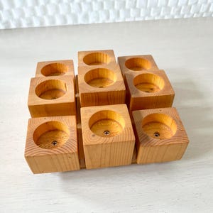 May include: A wooden candle holder with nine individual candle holders. The candle holder is made of natural wood and has a rustic look.