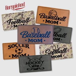 May include: Rectangular plaques with sports themes, including football, basketball, baseball, soccer, softball, and hockey. Each plaque features a sport-specific graphic and the word "MOM". The "Barnpicked Art" logo is in the upper left corner.