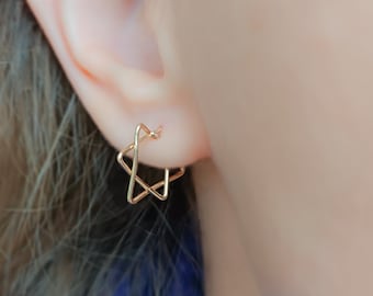 Könnte beinhalten: Goldene Stern-förmige Creolen. Die Ohrringe sind klein und zart und perfekt für den Alltag.