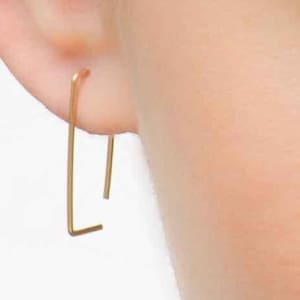 May include: A pair of gold-toned minimalist earrings with a simple rectangular shape.