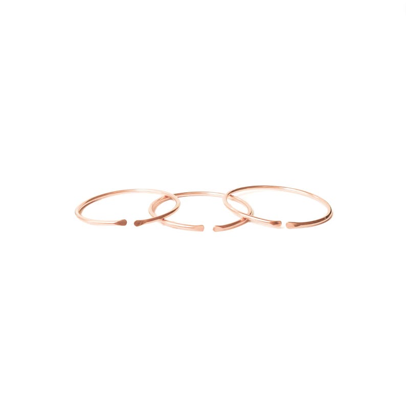 May include: Set of three thin, rose gold, open circle rings.