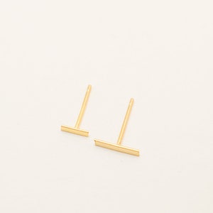 Op de afbeelding: Een paar gouden staaf oorbelletjes. De oorbelletjes zijn simpel en minimalistisch, met een dun staafje ontwerp.