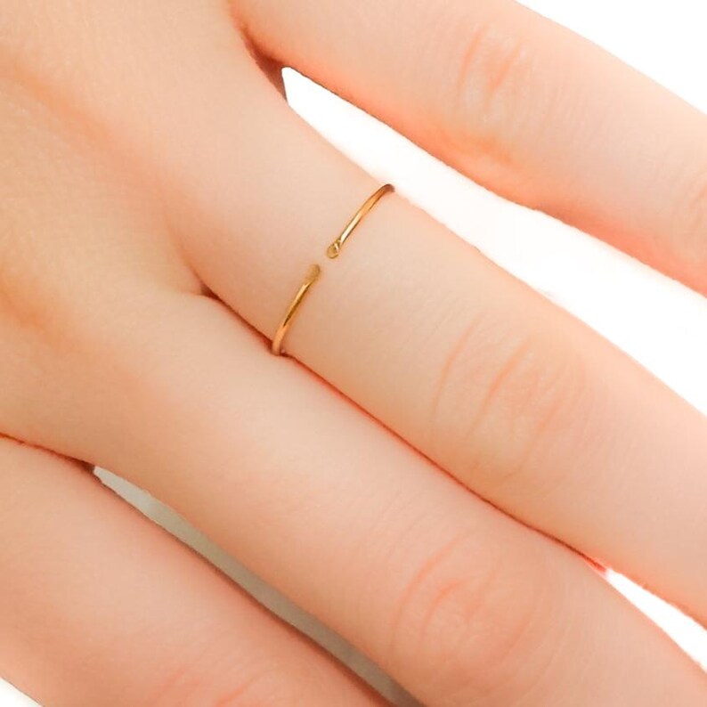 May include: A gold-toned open ring, worn on a finger.