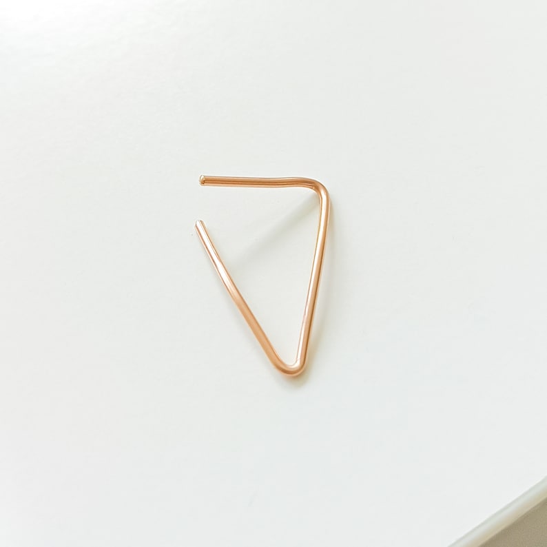 Op de afbeelding: Een eenvoudige, minimalistische driehoekige oorbel gemaakt van ros&eacute;goud.