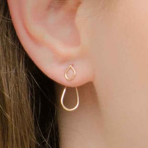 May include: A pair of gold teardrop shaped earrings with a dangling teardrop design.