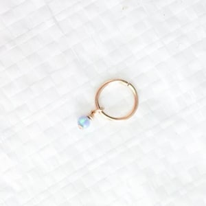 Puede incluir: Un aro de oro para la oreja con un peque&ntilde;o abalorio de cuentas azules iridiscentes.