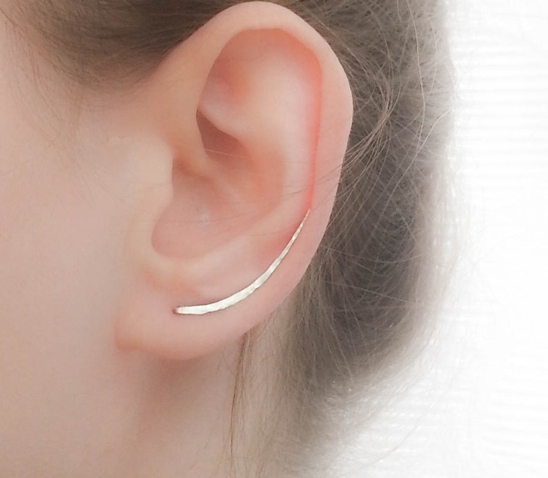 Long silver climber earrings shown on a model climbing up her ear. Hammered and tapered.