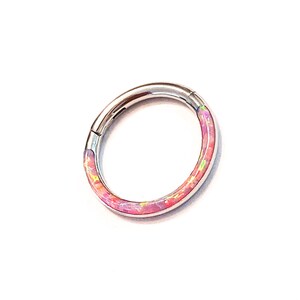 May include: A silver ring with a pink and white opal inlay. The ring is a seamless hoop with a hinged closure.