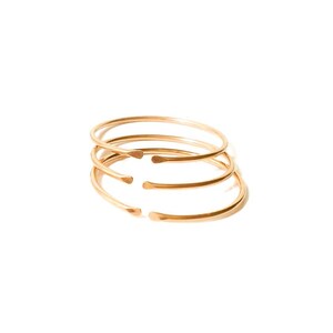 May include: Four gold-toned metal bangles stacked on top of each other.