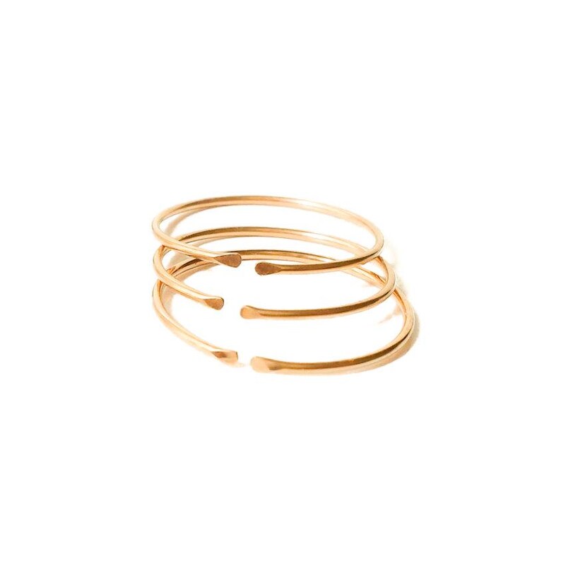 May include: Four gold-toned metal bangles stacked on top of each other.