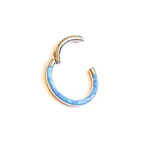 May include: A silver hoop earring with a blue opal inlay. The hoop is open and ready to be worn.