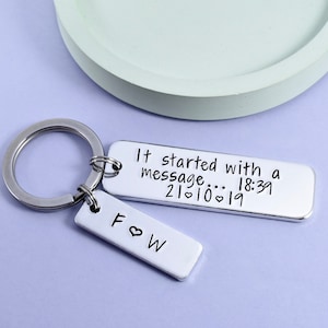 May include: Silver keyring with two tags. The larger tag reads "It started with a message... 18:39 21♥10♥19". The smaller tag reads "F♥W".