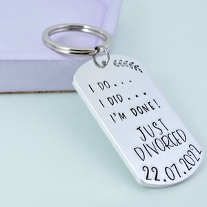 Może przedstawiać: Srebrny brelok do kluczy z wygrawerowanym tekstem "I do... I did... I'm done! Just Divorced 22.07.2021" na kształt wojskowej tabliczki.