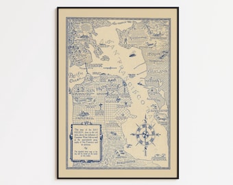 May include: A framed vintage map of San Francisco in blue ink on a beige background. The map includes illustrations of landmarks, a compass rose, and text. The frame is black.