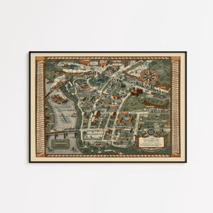 May include: A framed vintage map of a town, featuring detailed illustrations of buildings, streets, and a river. The map is in shades of green, brown, and beige, with decorative borders and text. The map is in a black frame.