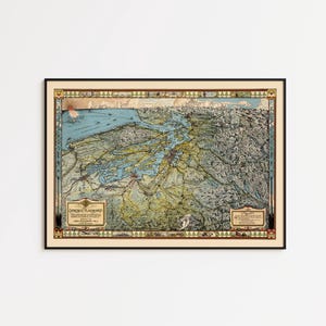 May include: A framed vintage map of the Puget Sound region, featuring detailed cartography in shades of blue, green, and beige. The map is enclosed in a black frame with decorative borders and text. A classic piece for home decor.
