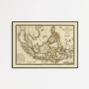 May include: Framed vintage map of Southeast Asia, showing detailed coastlines and geographical features. The map is in a black frame, with a cream background and text in the upper right corner. The map shows the islands of the Malay Archipelago.