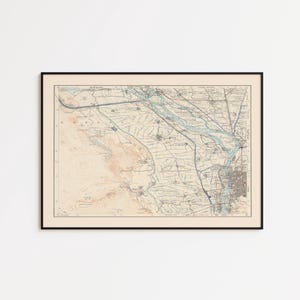 Może przedstawiać: Oprawiony, zabytkowy wydruk mapy w czarnej ramie. Mapa zawiera szczegółowe linie i cieniowania, z paletą kolorów beżu, błękitu i brązu. Mapa wydaje się przedstawiać obszar geograficzny, prawdopodobnie deltę rzeki lub region przybrzeżny.