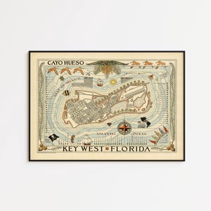 May include: A framed map of Key West, Florida, with the text "CAYO HUESO" at the top. The map features detailed illustrations of the island, compass rose, and surrounding waters. The map is in a black frame.