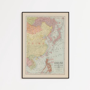 May include: A framed vintage map of the Japanese Empire, Philippine Islands, and Eastern China. The map features muted pastel tones of pink, yellow, and blue, with clear black text labels for geographical regions and the Pacific Ocean.