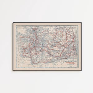 May include: A framed vintage map of Washington State, featuring a detailed road network in red and blue on a cream-colored background. The map is enclosed in a black frame, suitable for home decor.