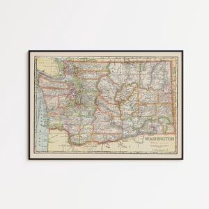 May include: A framed vintage map of Washington state featuring a cream-colored background with detailed topographical lines, county borders, and geographical labels. The map includes the text WASHINGTON in the lower right corner with a black frame.