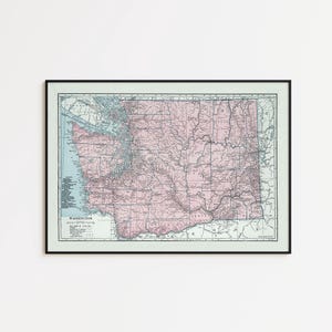 May include: A framed vintage-style map of Washington state featuring a pale pink landmass against a light blue water background. The map displays detailed geographical lines, county borders, and the text WASHINGTON in the lower left corner.