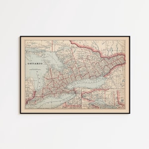 May include: A framed vintage map of Ontario, Canada, with a beige background and red and grey details. The map is enclosed in a black frame. The word "ONTARIO" is visible in the upper left corner.