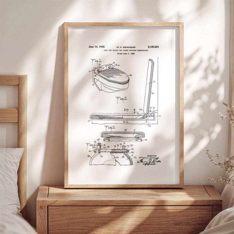 May include: A framed patent print featuring a detailed black and white diagram of a toilet seat design. The print includes technical drawings and labels, with the inventor's signature at the bottom. The wooden frame adds a classic touch to the artwork.