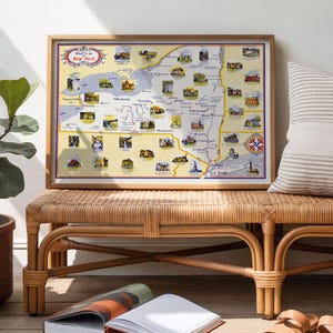Puede incluir: Un mapa vintage enmarcado del estado de Nueva York, con ilustraciones de lugares emblemáticos y atracciones. El mapa está en un marco de madera y descansa sobre un banco tejido. El mapa incluye el texto "New York".
