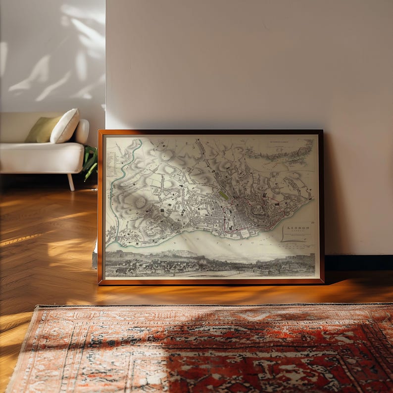 May include: A framed historical map of Lisbon, Portugal, featuring detailed black and white cartographic lines, topographical shading, and a panoramic cityscape illustration at the bottom, all enclosed within a simple dark brown wooden frame.