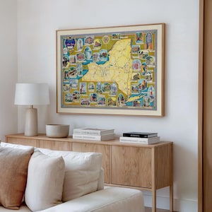 Puede incluir: Un mapa vintage enmarcado del estado de Nueva York, con un contorno amarillo e ilustraciones de lugares emblemáticos. El mapa está en un marco de madera clara, encima de un mueble de madera. La habitación está decorada en tonos neutros.