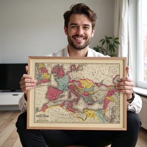 Op de afbeelding: Een ingelijste kaart van het Romeinse Rijk, met een gedetailleerde historische weergave van de gebieden van het rijk. De kaart zit in een houten lijst, met de titel "Map of the Roman Empire" zichtbaar. De kaart gebruikt een kleurenschema van roze, geel en blauw.