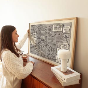 May include: A framed vintage map of the "The Parks of the Living Giants" in Sequoia National Park, California. The map shows the location of the Giant Forest, Moro Rock, and other landmarks. The map is hanging on a wall above a wooden dresser.