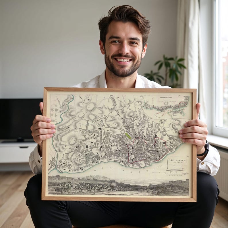May include: A framed vintage-style map of Lisbon, Portugal, featuring detailed black and white cartographic illustrations of the city streets, topography, and a panoramic view of the harbour at the bottom, with the text LISBON printed in the corner.