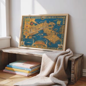 May include: A framed vintage map of Newport, Rhode Island, in shades of blue, yellow, and red. The map is displayed on a rustic wooden crate, with a stack of colorful books and a beige blanket. The map is the focal point.