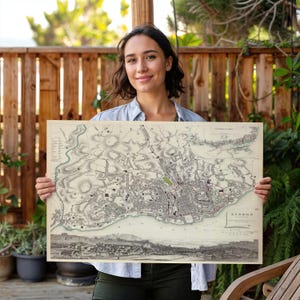 May include: A vintage-style rectangular map of Lisbon printed on cream-coloured paper. The map features detailed black ink illustrations of city streets, topography, and a panoramic view of the harbour at the bottom, with the text LISBON printed.