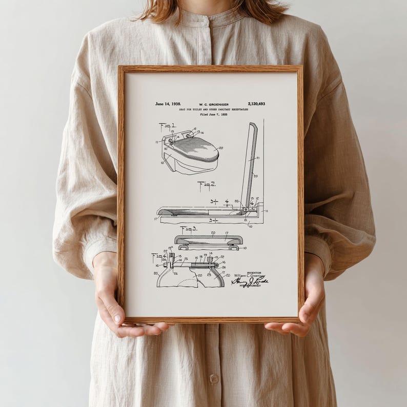 May include: A framed black and white patent print of a toilet design, dated June 14, 1938. The print includes multiple diagrams and technical drawings of the toilet's components, with labels and annotations. The frame is a warm brown color.