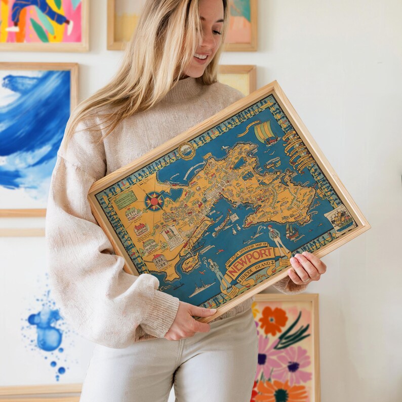 May include: A framed vintage map of Newport, Rhode Island, in a light wood frame. The map features a blue background with yellow and red details, including illustrations of ships and landmarks. The text "Newport, Rhode Island" is visible.