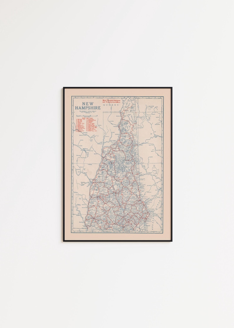 May include: Framed vintage map of New Hampshire, featuring a detailed road network in red and blue against a beige background. The map includes the state name and other text in the upper left corner, encased in a black frame.