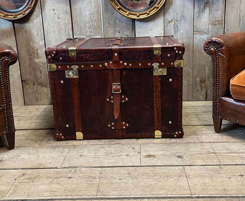 Full-grain hand dyed leather steamer trunk with hinged lift-up lid, brass stud edging and buckled straps, made in England