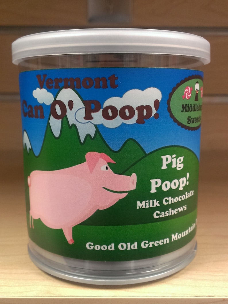 May include: A clear plastic container with a white lid filled with milk chocolate cashews. The container has a green, blue, and white label with the text "Vermont Can O' Poop! Pig Poop! Milk Chocolate Cashews Good Old Green Mountain Sweets".