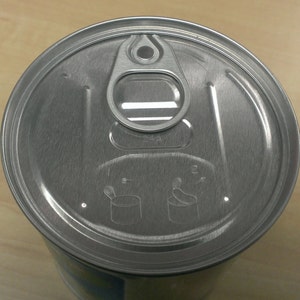 May include: A silver can lid with a pull tab and instructions for opening. The instructions show a spoon and a can with an arrow pointing to the side.