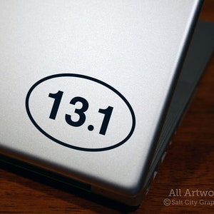 Photo of Salt City Graphics 13.1 Half Marathon decal featuring the number 13.1 inside an oval. The decal is Black and shown on the bottom right of a silver laptop lid. Photo and artwork copyright Salt City Graphics®.