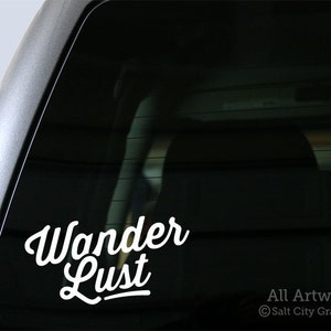 May include: White vinyl sticker with the text "Wanderlust" in a cursive font on a black car window.