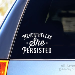 Photo of white vinyl decal of the popular phrase Nevertheless She Persisted shown on SUV window